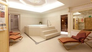 Ein Wellnessraum mit einer großen Badewanne, einer Liege und einer Dachfensterdecke.