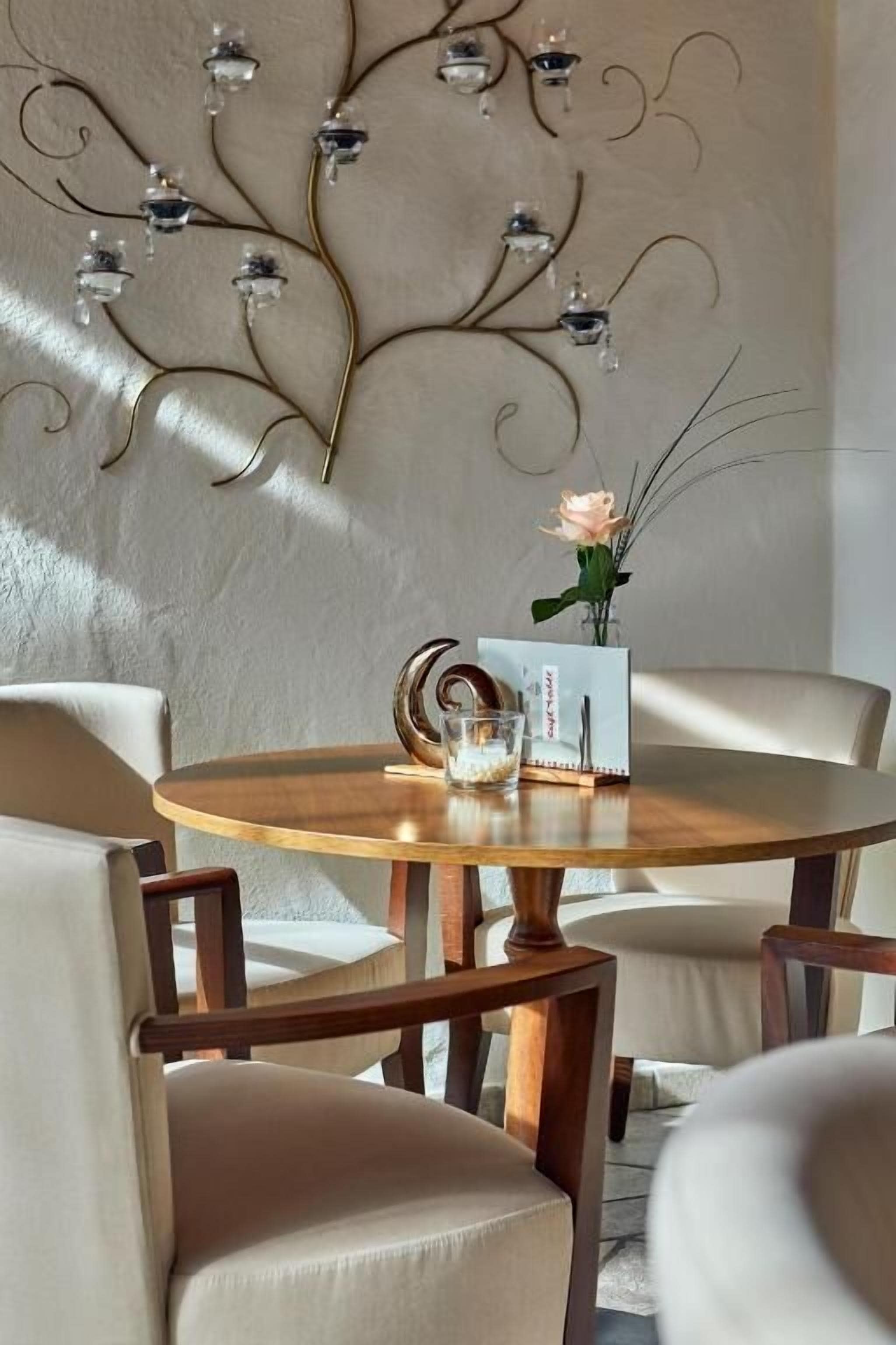Une table ronde en bois, ornée d’un vase de fleurs et d’un présentoir à menus.