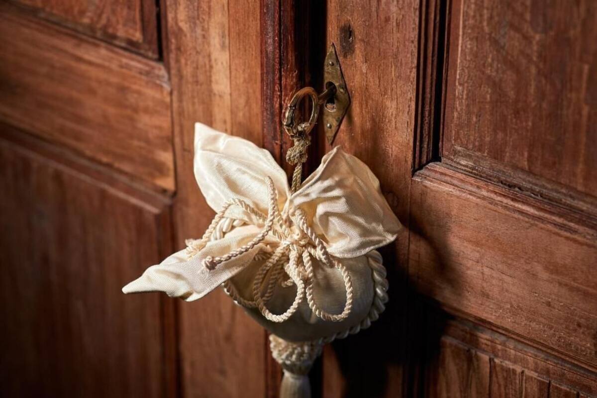 A wooden door with a brass doorknob and a decorative fabric bow hanging on it.