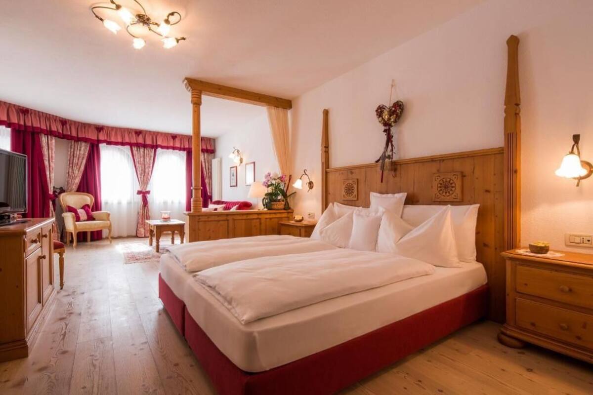 A bedroom with a large bed, wooden headboard, and a dresser.