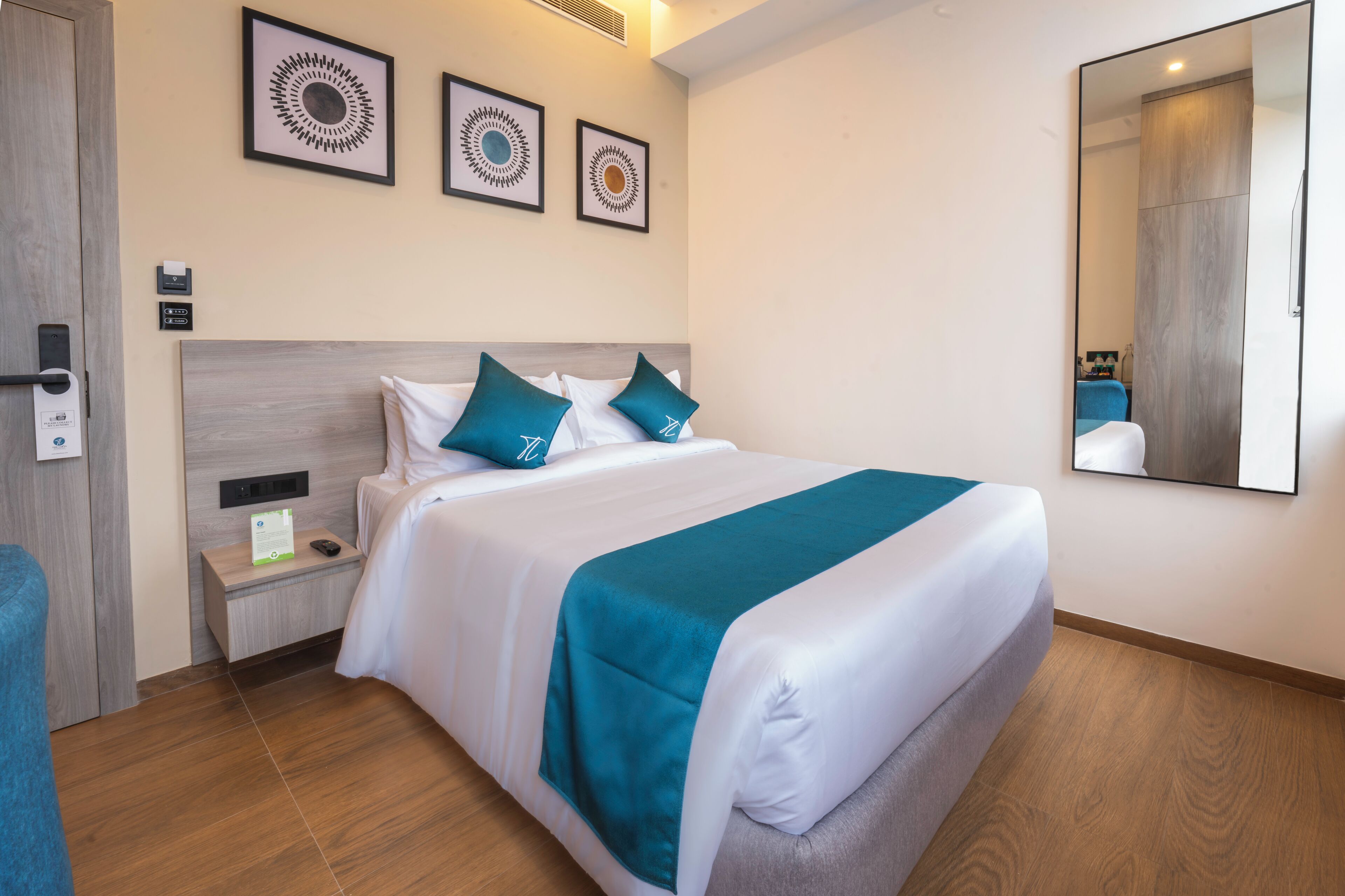 A hotel room with a large bed, a nightstand, a mirror, and wall-mounted artwork.