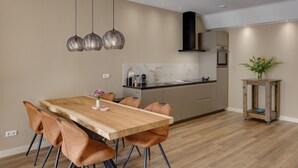 Una cocina moderna con una mesa y sillas de madera, horno empotrado e iluminación colgante.