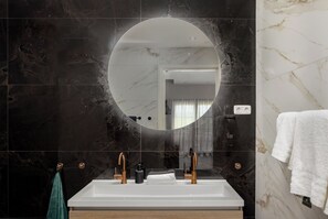 Un baño moderno con un espejo grande, un lavabo blanco y un perchero para toallas.