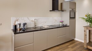 Una cocina moderna con salpicadero de mármol, electrodomésticos de acero inoxidable y una mesa de madera con flores.