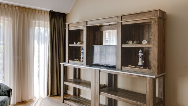 Una habitación con una consola de madera, estanterías y un televisor.