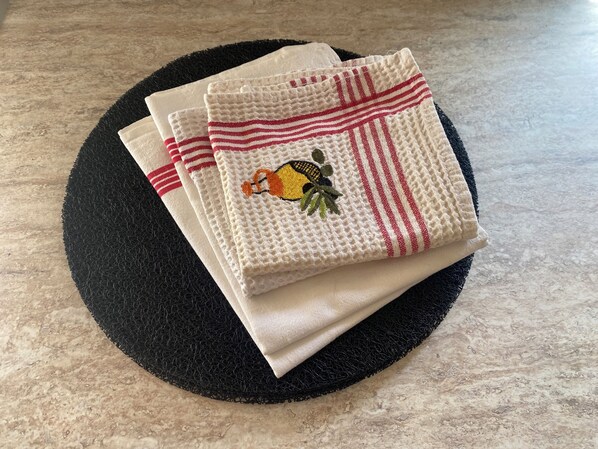 A stack of folded towels with a woven texture and a decorative embroidered towel featuring a sun and leaves.