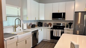 A modern kitchen with white cabinetry, stainless steel appliances, and a wooden floor.