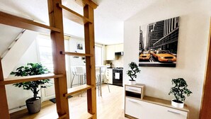 Una cucina moderna con mobili bianchi, un'area pranzo con sedie bianche e una scala che conduce a un piano superiore.
