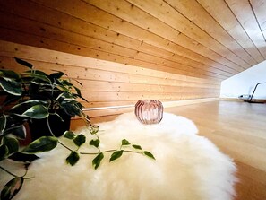 Une pièce aux murs recouverts de lambris en bois, un tapis blanc et moelleux, et une plante en pot.
