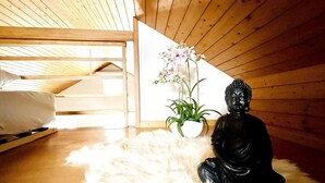 Un'area dedicata alla meditazione con una statua, una pianta in vaso e un letto in una stanza in legno.