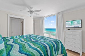 A bedroom with a bed, a ceiling fan, a TV on a dresser, and a view of the ocean. - Shoreline Towers 1081 (Destin)