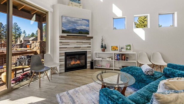 Amplia sala de estar con chimenea, televisor grande y zona de estar con sofá y sillones azules.