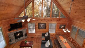 Un intérieur de chalet chaleureux avec une cheminée, des murs en bois, un téléviseur et un coin repas.