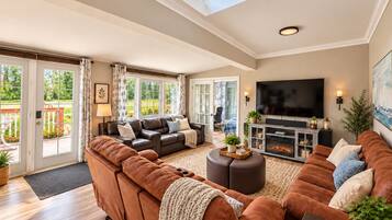 A spacious living room with a large sofa set, a fireplace, and a television.