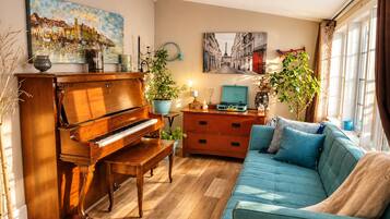 A living room with a grand piano, a sofa, a dresser, and two potted plants.