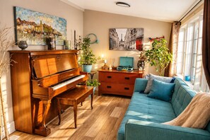 A living room with a grand piano, a sofa, a dresser, and two potted plants.