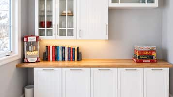 A kitchen with white cabinets, a popcorn machine, and a row of books on the counter.