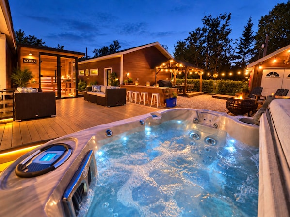 A hot tub with a control panel, surrounded by outdoor seating and a bar area.