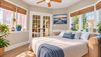 A bedroom with a bed, a ceiling fan, a window with a view, and a door leading to a closet.