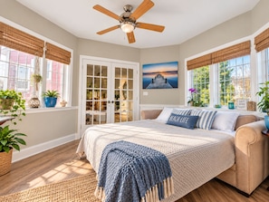 A bedroom with a bed, a ceiling fan, a window with a view, and a door leading to a closet. - Ice Fishing Getaway | Hot Tub, Sauna + Trailer Parking (Winnipeg Beach)