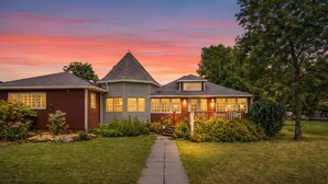 Une maison à deux étages avec une cheminée centrale, un porche couvert et une pelouse bien entretenue.