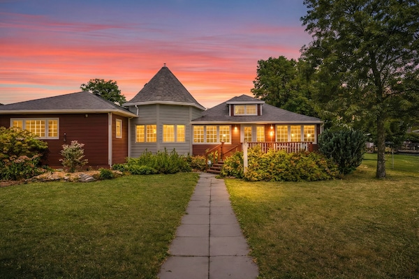 Front yard with water views, tall trees, hydrangeas, lavender, and flowers.