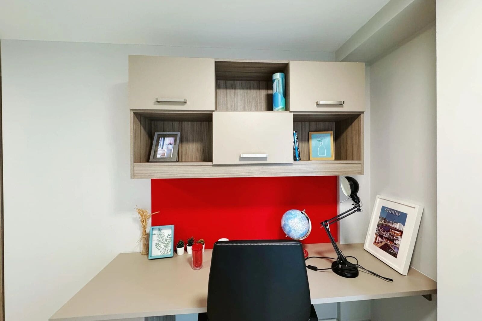Ein Arbeitsraum mit Schreibtisch, Stuhl und einer roten Wand.