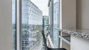 A room with a large window, a black chair, and a view of a cityscape. - 2BR | Gym, Pool | Bellevue | Sophari Towers I (Bellevue)
