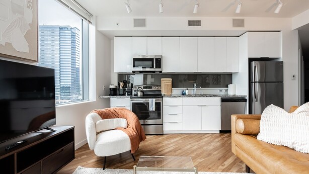 A modern kitchen with white cabinets, stainless steel appliances, and a city view. - 2BR | Gym, Pool | Bellevue | Sophari Towers I (Bellevue)