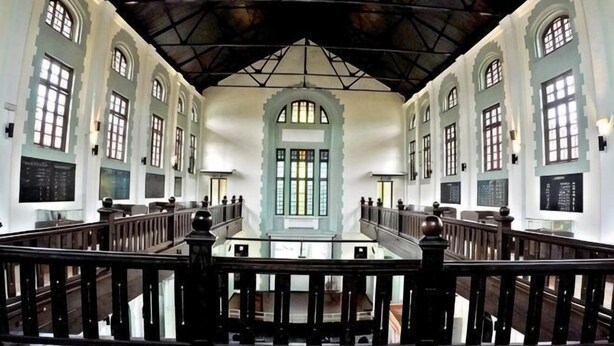 A spacious interior with high ceilings, arched windows, and a central staircase.