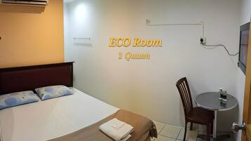 A room with a bed, a chair, a small table, and a wall-mounted TV.