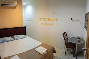 Une pièce comprenant un lit, une chaise, une petite table et un téléviseur fixé au mur.