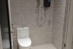 Un espacio de ducha pequeño y cerrado, con inodoro y ducha de mano.