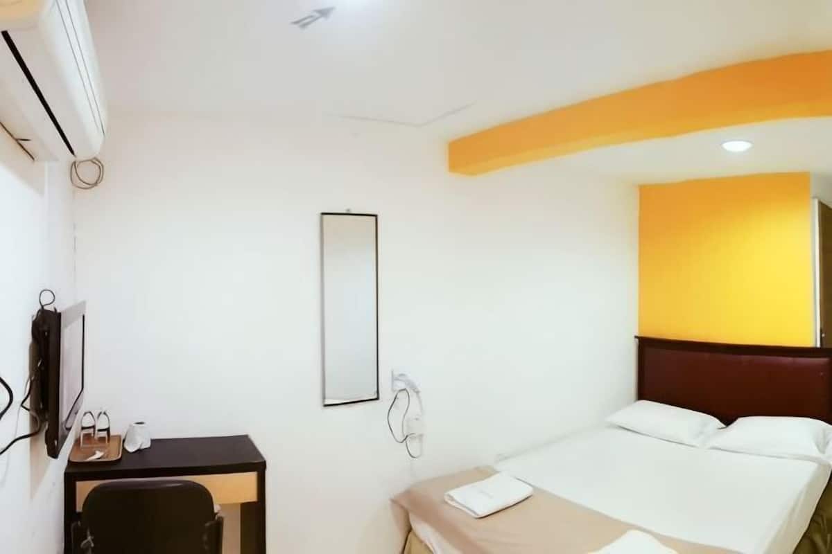 Een hotelkamer met een bed, een bureau, een stoel, een spiegel en een airconditioning.