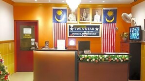 A reception area with a curved desk, Malaysia and USA flags, a 'TwinStar' sign, and a television monitor.