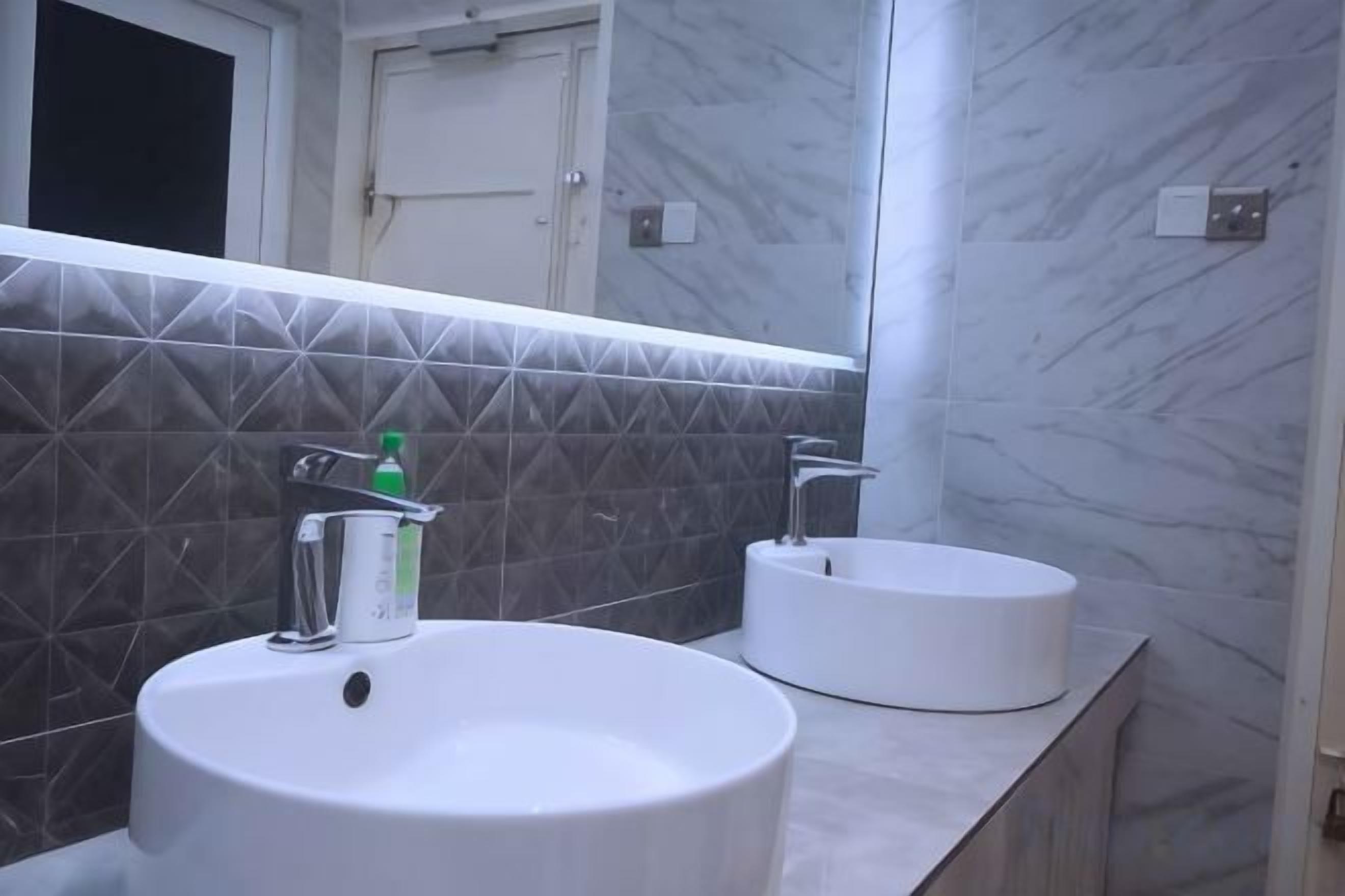 A bathroom with two sinks, a mirror, and a door.