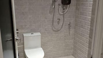 A bathroom with a toilet, a shower, and a wall-mounted control panel.