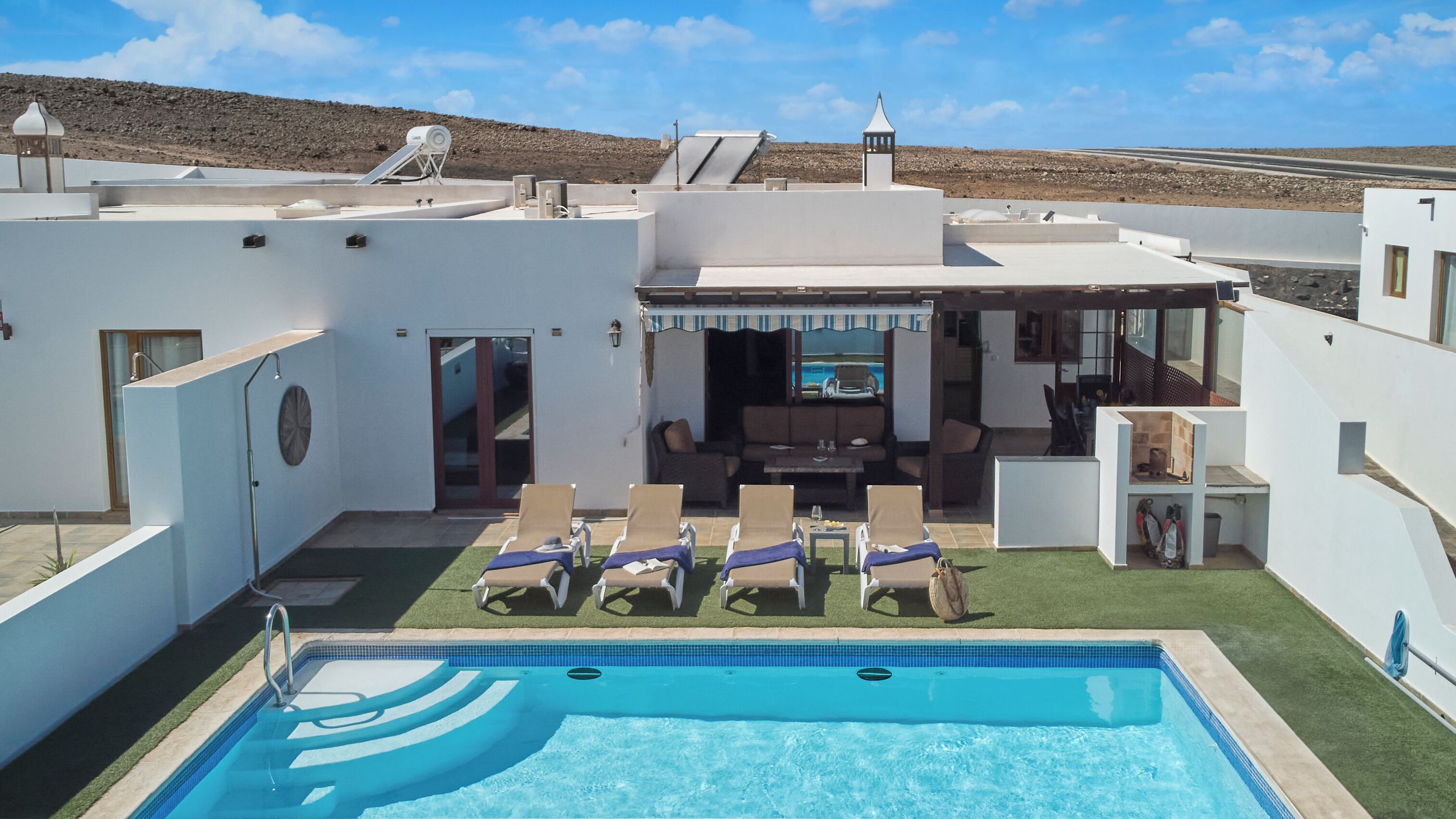 Zona de piscina amb gandules, zona de menjador i vistes al paisatge circumdant.