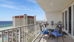 A balcony with a table and chairs, overlooking a beach and high-rise buildings. - Laketown Wharf 1523 (Panama City Beach)