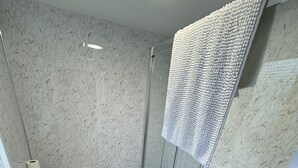 A modern bathroom with a glass shower enclosure, a white sink, and a toilet. - Seaside Hotel  (Brighton)