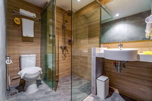A modern bathroom with a glass-enclosed shower, a toilet, and a sink with a mirror above. - Yello Hotel Harbour Bay Batam (Batam)
