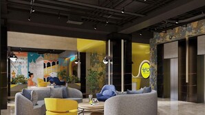 A modern lobby with a circular seating area, a yellow accent chair, and a mural depicting a cityscape. - Yello Hotel Harbour Bay Batam (Batam)