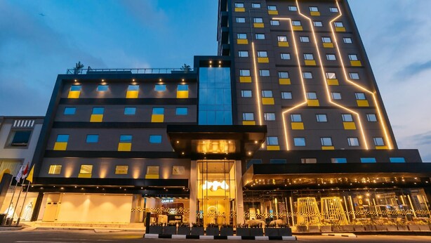 A modern hotel with a prominent 'Hello' sign, multiple floors, and a well-lit entrance. - Yello Hotel Harbour Bay Batam (Batam)
