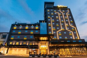 Un hotel moderno con un cartello ben visibile con la scritta 'Hello', diversi piani e un ingresso luminoso.