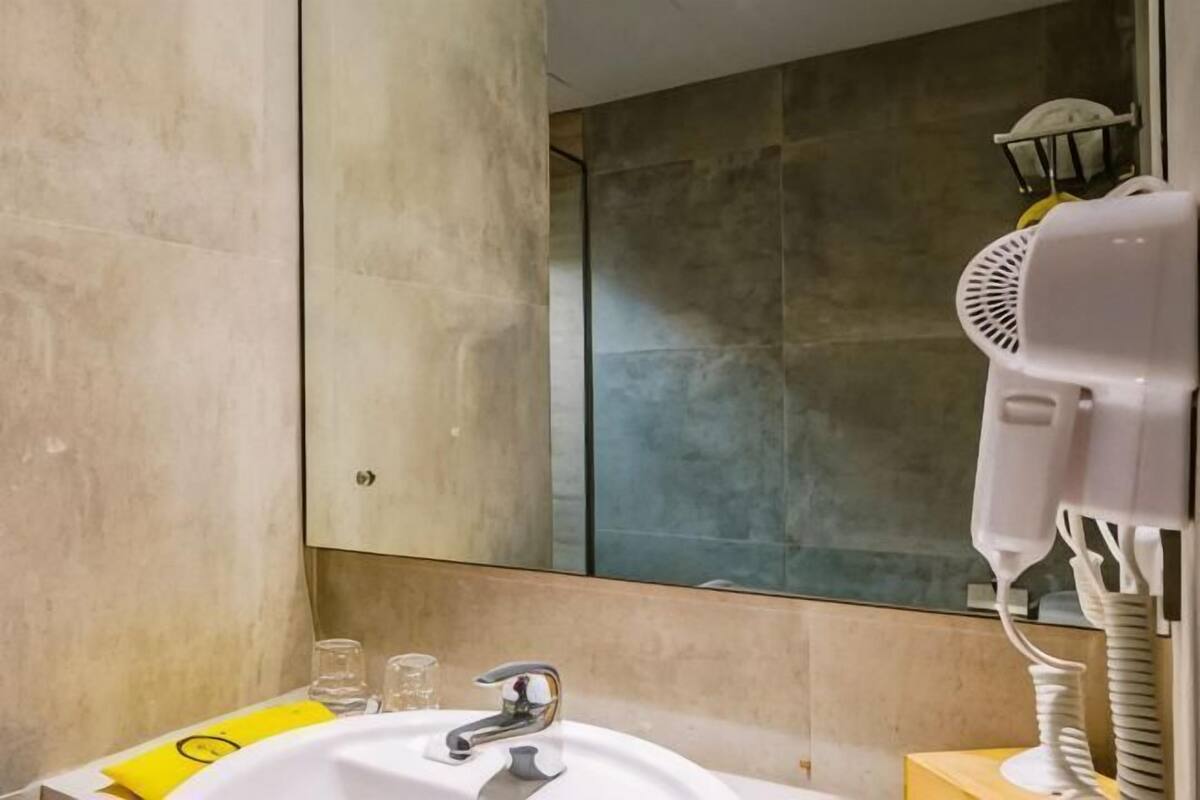 Un baño con un lavamanos blanco, un espejo y un secador de pelo.