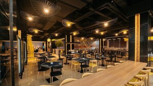 A spacious restaurant with multiple dining tables and chairs, modern pendant lighting, and a bar area. - Yello Hotel Harbour Bay Batam (Batam)