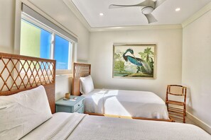 A hotel room with two beds, a window with a view, a ceiling fan, and a painting of a bird. - View West #1 (Indian Shores)
