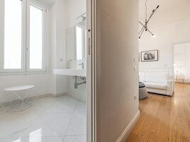 Un bagno moderno con un lavandino bianco, uno specchio e uno sgabello bianco.