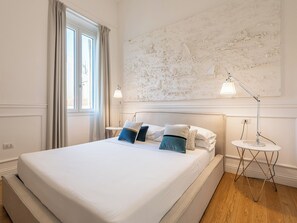 Une chambre à coucher bien aménagée, avec un grand lit, deux lampes de chevet et un tableau abstrait moderne accroché au mur.