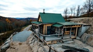 A rustic cabin with a green roof, wooden deck, and a fire pit. - SKYLINE LODGE~ Spectacular Mountain Escape! (fletcher)